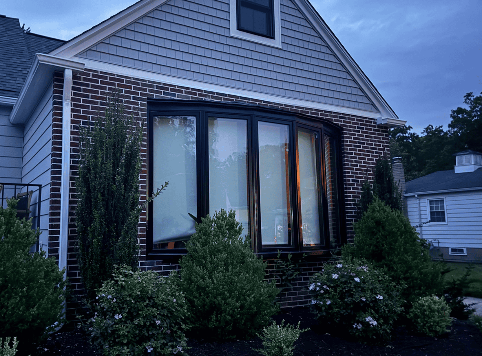 Example Co Home Exterior Beautiful brick house with large bay window and well-maintained garden.