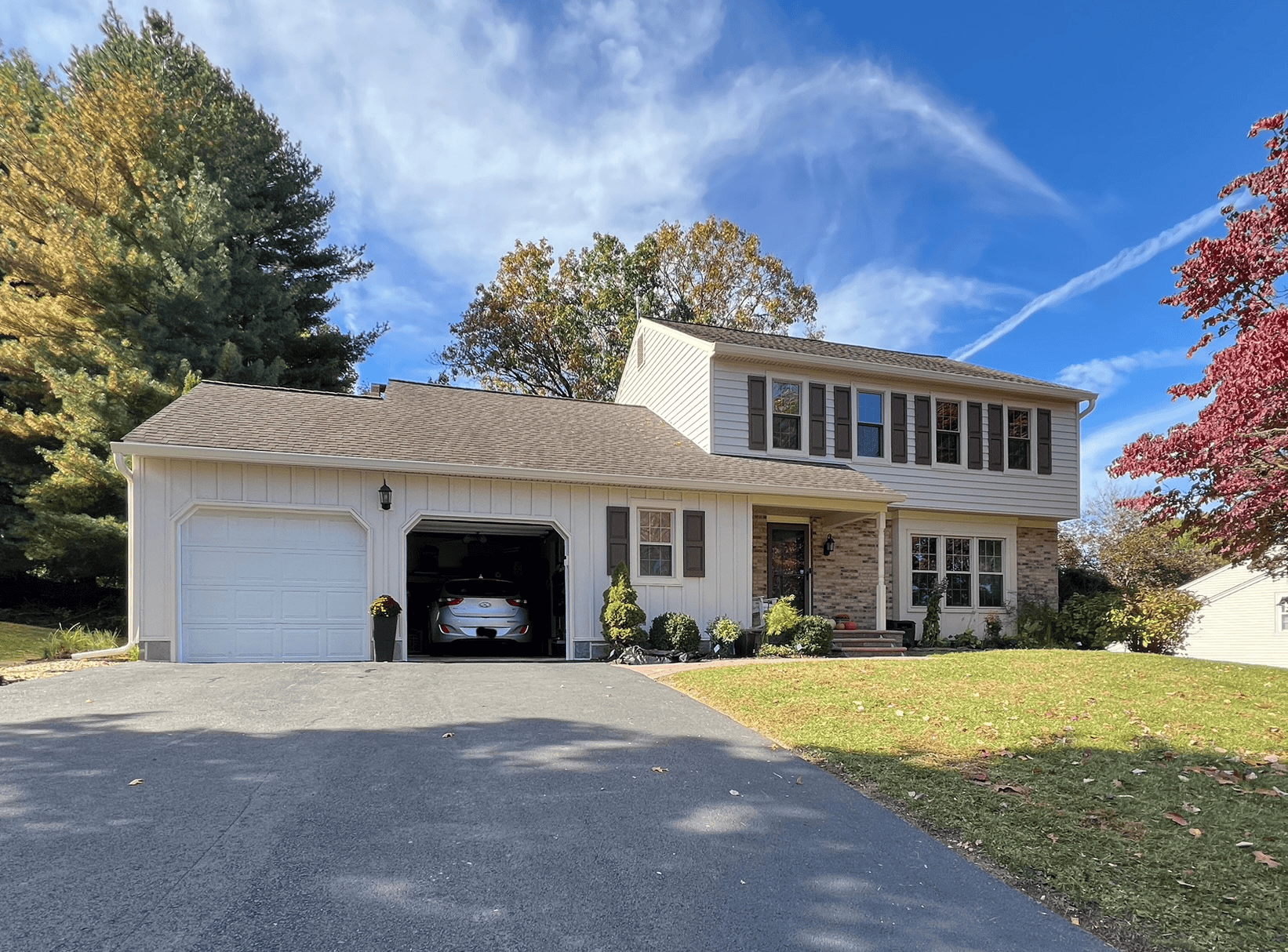 Example Co Home Exterior Beautiful suburban house with a two-car garage, surrounded by trees and a well-maintained lawn.
